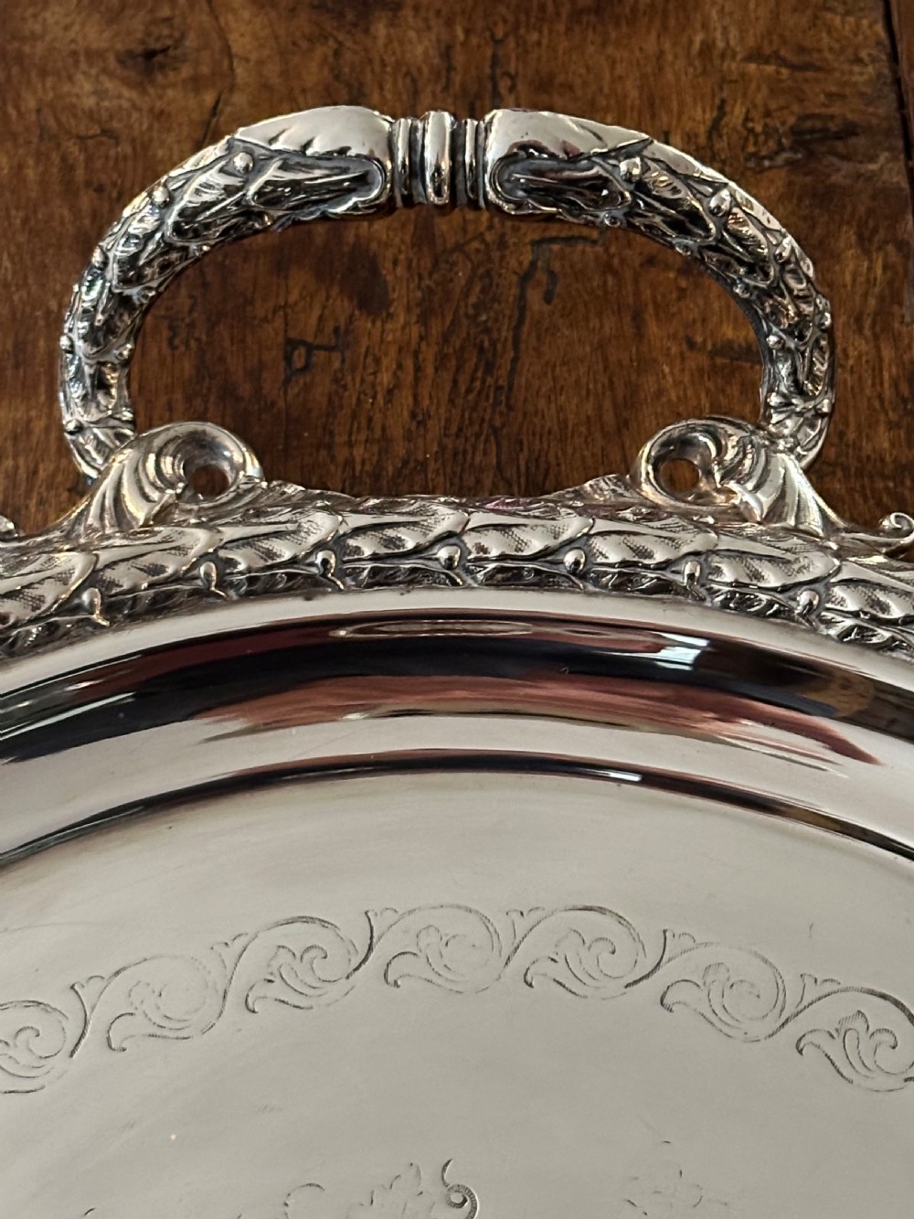 A large oval Edwardian silver-plated serving tray with detailed scrollwork rims, surface foliage engraving, and two cast side handles. View III