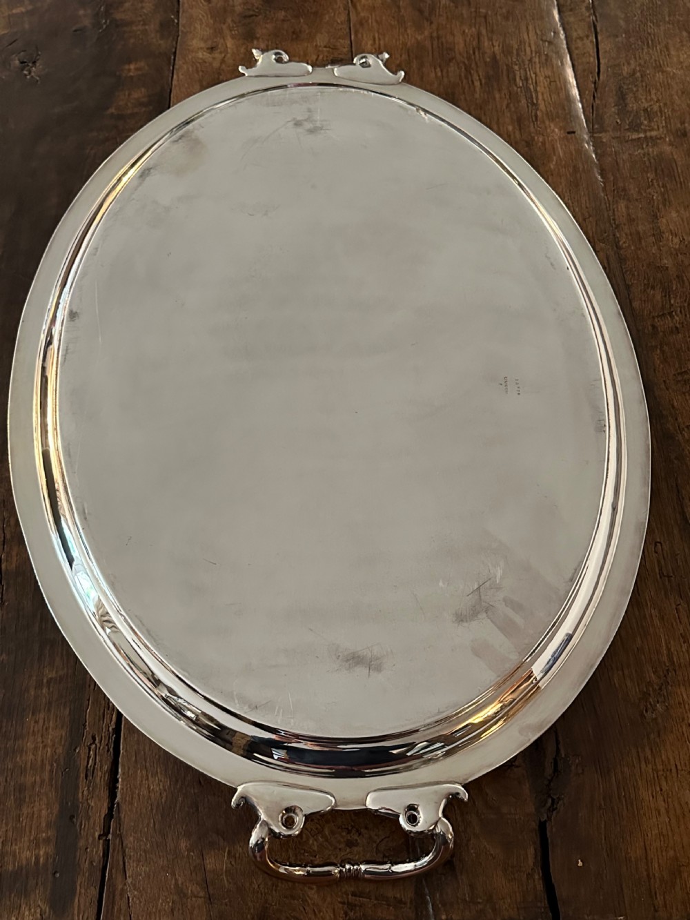 A large oval Edwardian silver-plated serving tray with detailed scrollwork rims, surface foliage engraving, and two cast side handles. View V