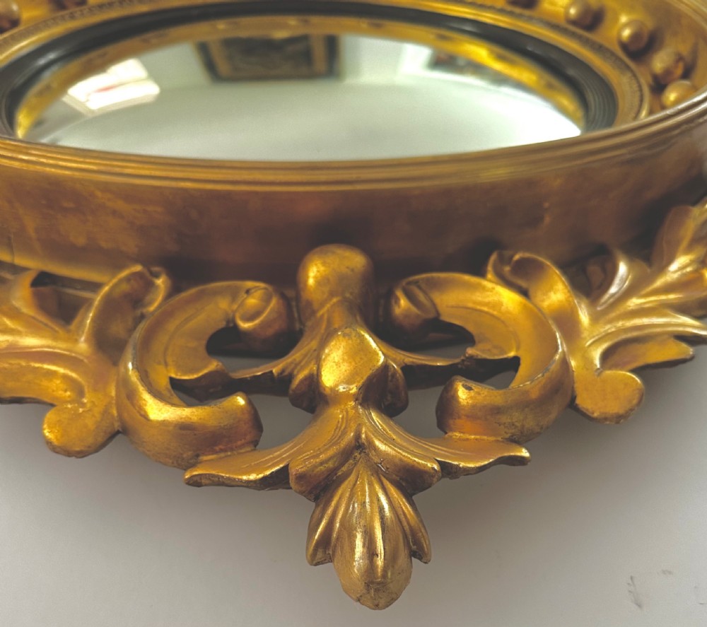 A circular Regency giltwood convex mirror featuring a carved eagle cresting, acanthus leaf scrolls, and ball mouldings around an ebonised inner slip. View VI