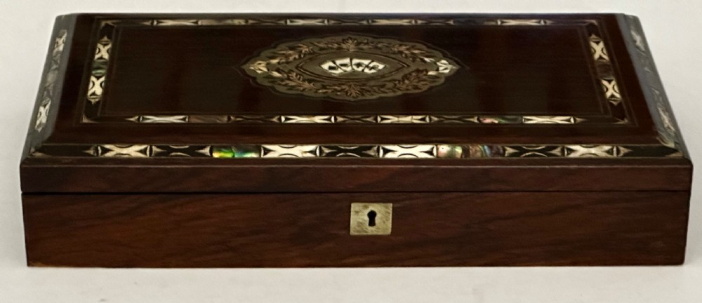 A rectangular dark rosewood games box featuring mother-of-pearl and abalone inlaid borders with a central playing card motif medallion and a brass keyhole. View III