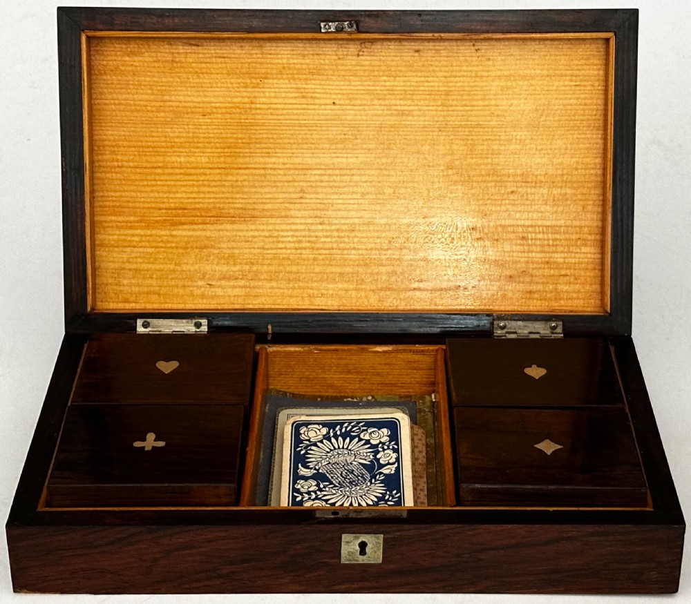 A rectangular dark rosewood games box featuring mother-of-pearl and abalone inlaid borders with a central playing card motif medallion and a brass keyhole. View V