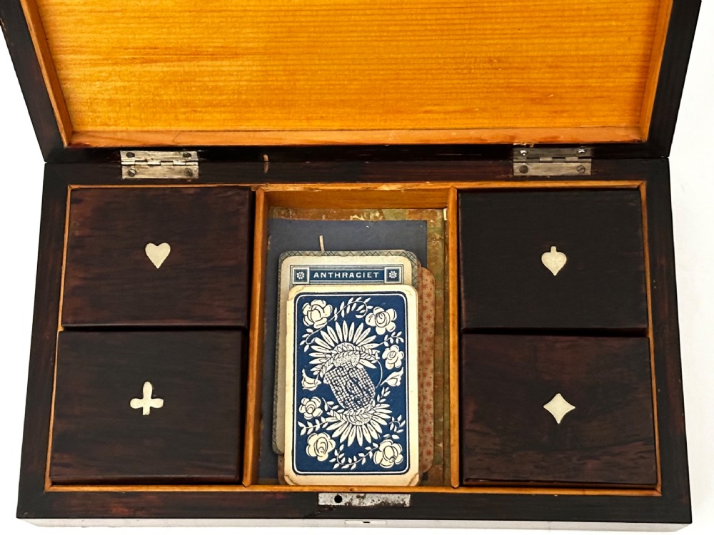 A rectangular dark rosewood games box featuring mother-of-pearl and abalone inlaid borders with a central playing card motif medallion and a brass keyhole. View VI