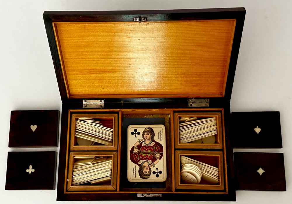 A rectangular dark rosewood games box featuring mother-of-pearl and abalone inlaid borders with a central playing card motif medallion and a brass keyhole. View VII