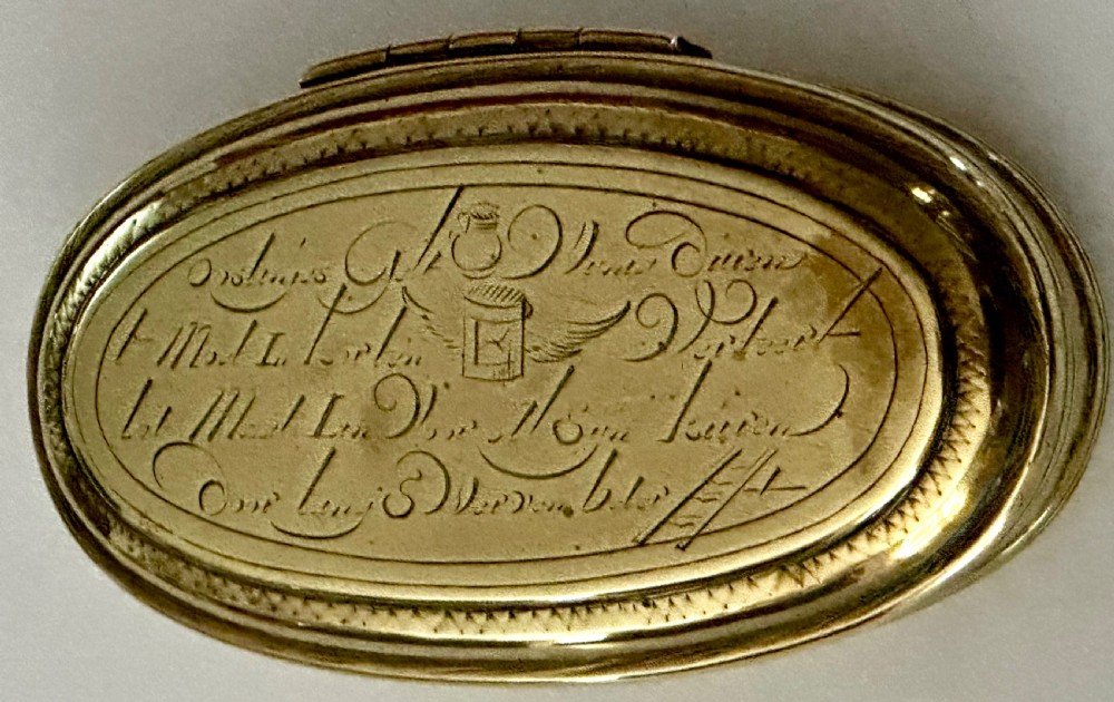 An 18th-century oval brass tobacco box featuring hand-engraved Dutch calligraphy and a hinged lid. View IV