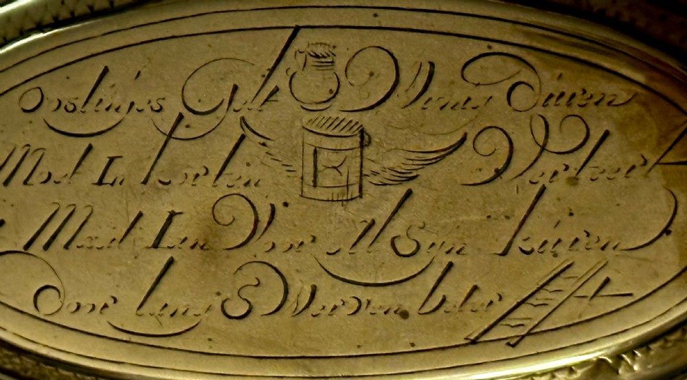 An 18th-century oval brass tobacco box featuring hand-engraved Dutch calligraphy and a hinged lid. View VI