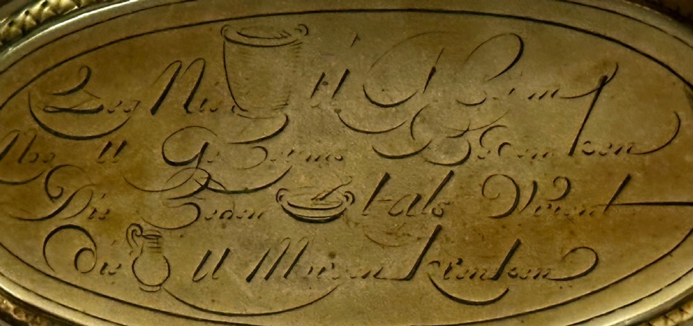 An 18th-century oval brass tobacco box featuring hand-engraved Dutch calligraphy and a hinged lid. View VII