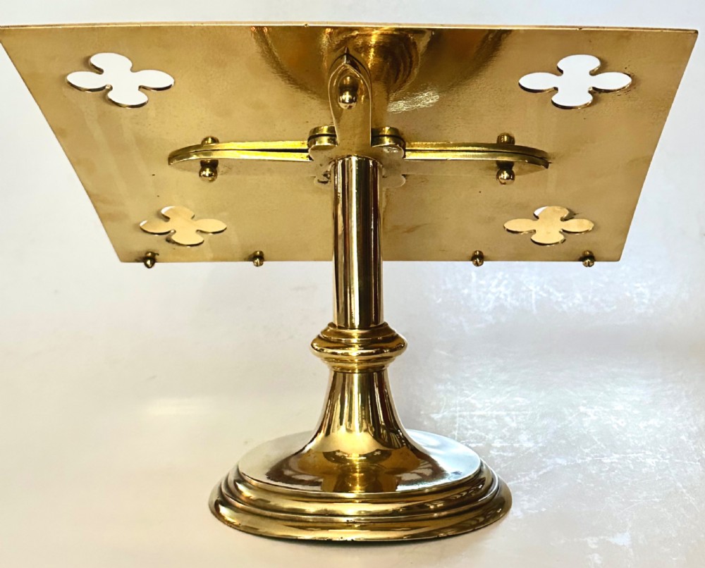 A polished brass tabletop lectern featuring quatrefoil corner cutouts, an engraved Gothic monogram inside a central medallion, a scalloped lip, and a stepped circular pedestal base. View IV