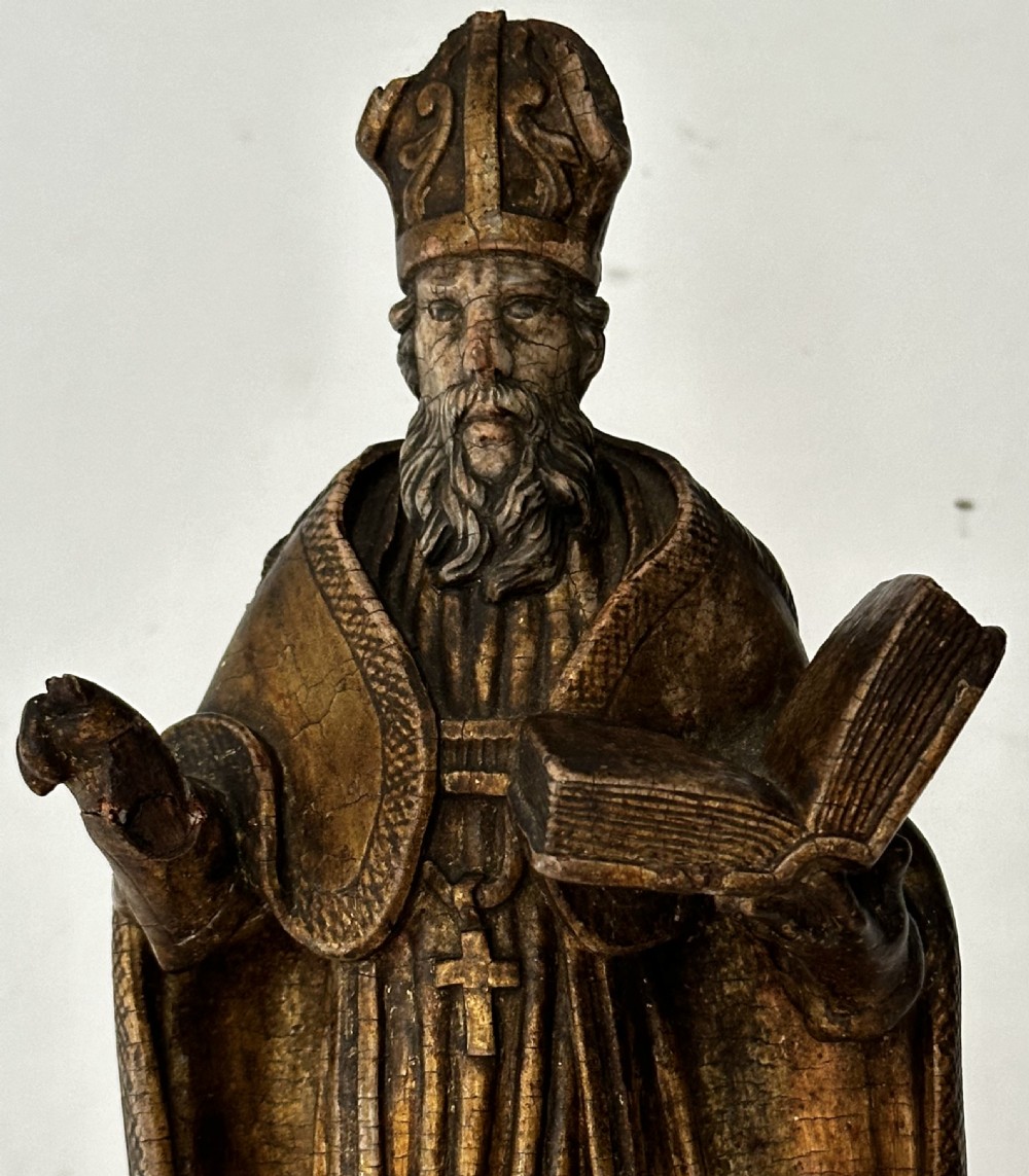 An 18th-century carved wooden statue depicting Saint Nicholas wearing a bishops mitre, holding a cross staff and open book, with aged dark brown and gilt finishes. View II