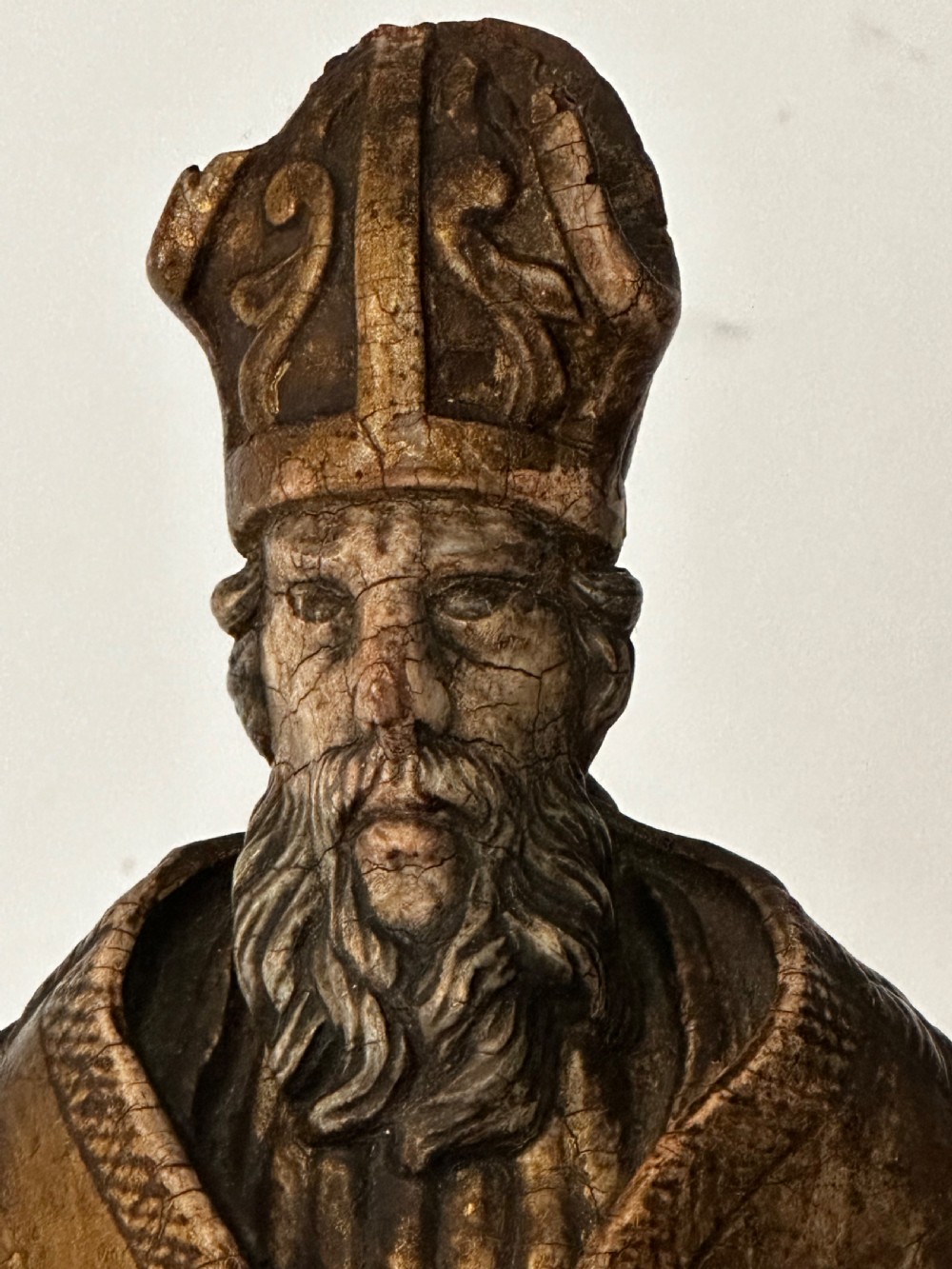 An 18th-century carved wooden statue depicting Saint Nicholas wearing a bishops mitre, holding a cross staff and open book, with aged dark brown and gilt finishes. View III