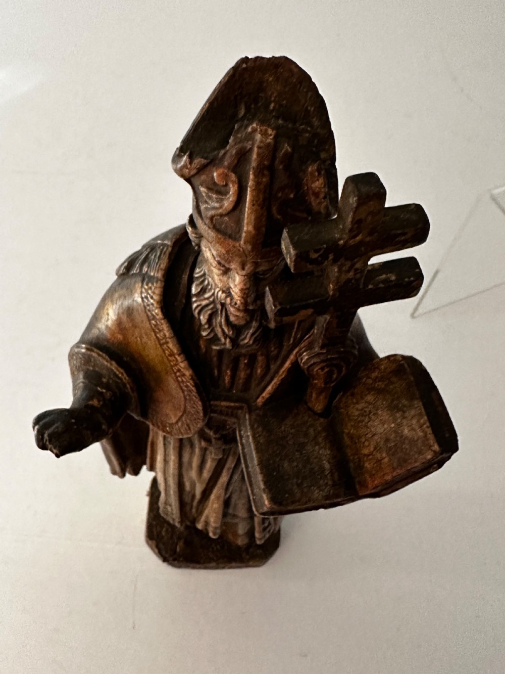 An 18th-century carved wooden statue depicting Saint Nicholas wearing a bishops mitre, holding a cross staff and open book, with aged dark brown and gilt finishes. View VII