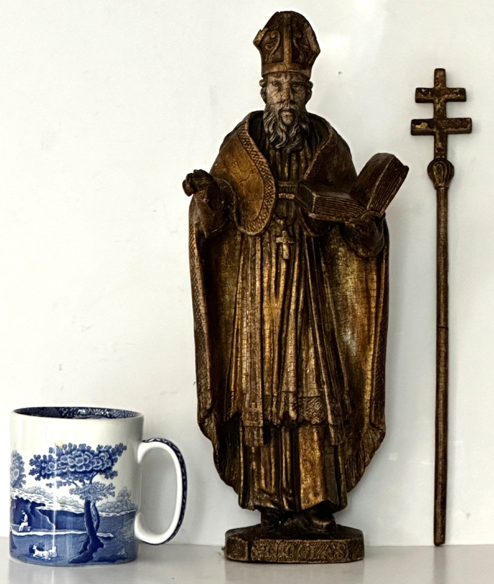 An 18th-century carved wooden statue depicting Saint Nicholas wearing a bishops mitre, holding a cross staff and open book, with aged dark brown and gilt finishes. View VIII