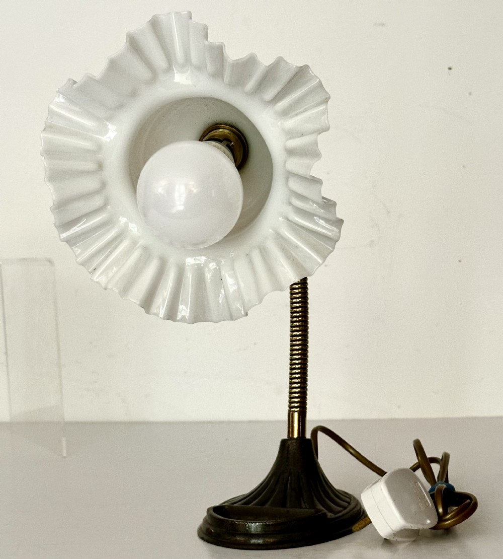 A brass gooseneck desk lamp with a flexible coiled arm, dark cast base featuring a built-in tray, and a ruffled white glass shade. View IV
