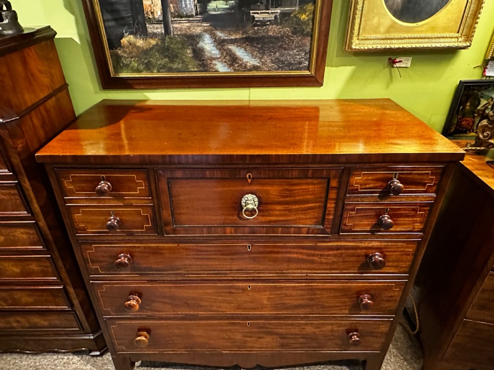 A Regency mahogany Scotch chest of drawers featuring boxwood inlay, a deep central drawer with a brass lion head pull, and multiple outer drawers with turned wooden knobs. View III