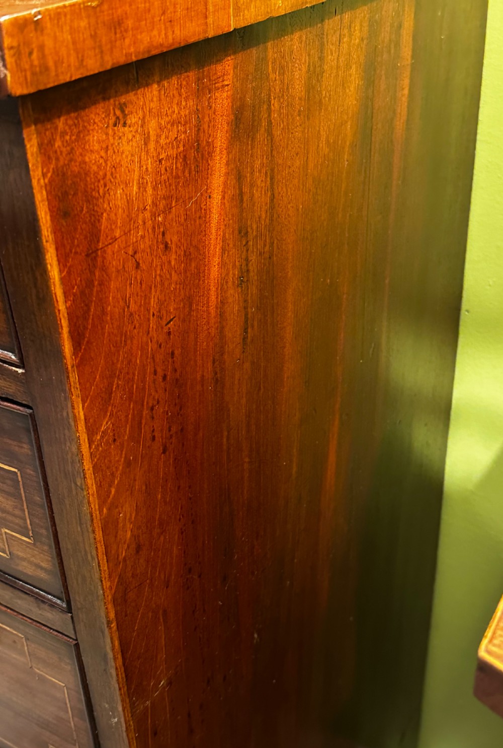 A Regency mahogany Scotch chest of drawers featuring boxwood inlay, a deep central drawer with a brass lion head pull, and multiple outer drawers with turned wooden knobs. View VII
