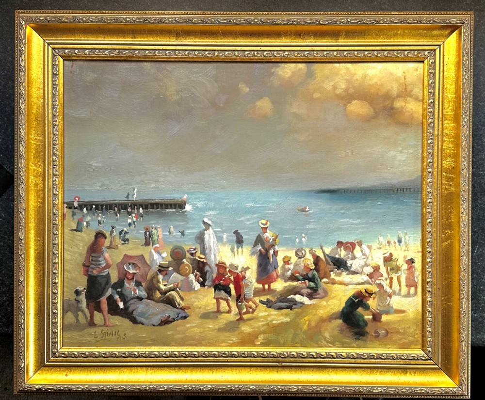 An impressionist oil painting depicting crowds of figures gathered on a sandy beach beside a blue sea, presented in an ornate gold gilt frame.