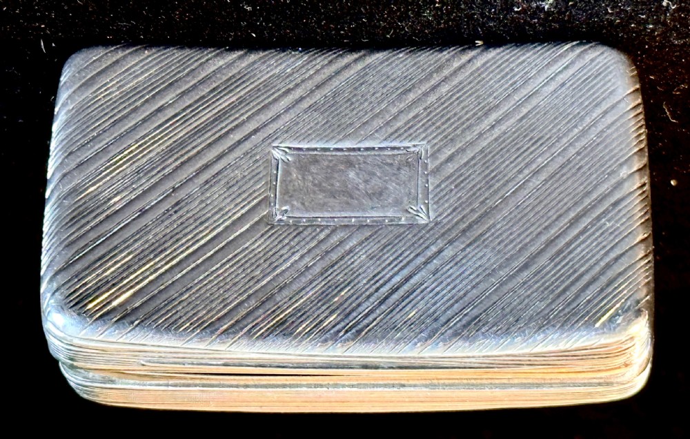 A rectangular antique silver snuff box featuring diagonal engine-turned reeding and a central unengraved rectangular cartouche.