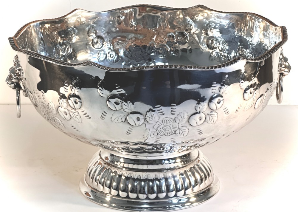 A silver-plated pedestal punch bowl featuring embossed floral repousse decoration, a scalloped rim, and twin lion mask drop-ring handles. View IV