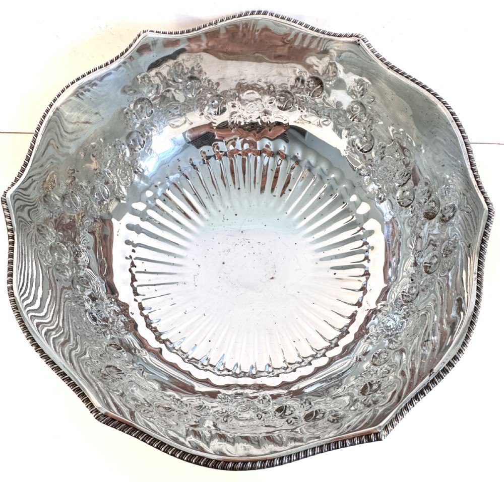 A silver-plated pedestal punch bowl featuring embossed floral repousse decoration, a scalloped rim, and twin lion mask drop-ring handles. View VII