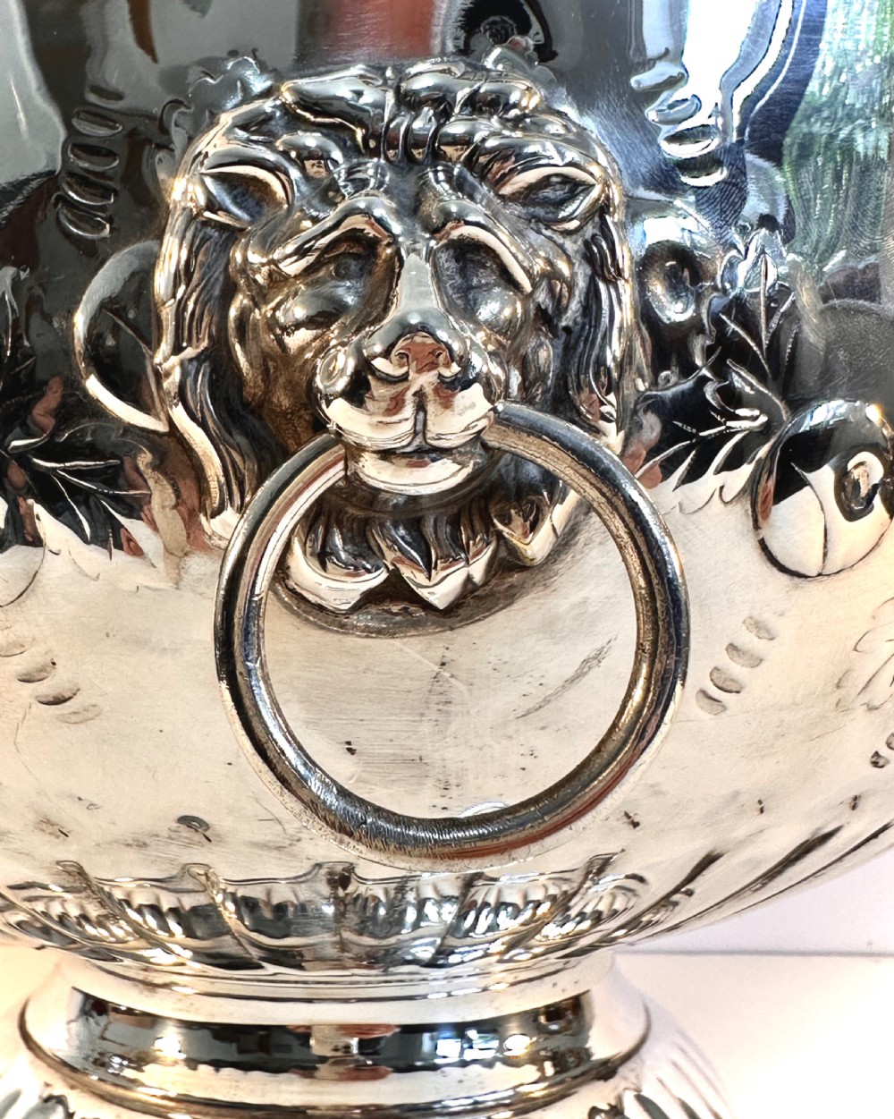 A silver-plated pedestal punch bowl featuring embossed floral repousse decoration, a scalloped rim, and twin lion mask drop-ring handles. View VIII