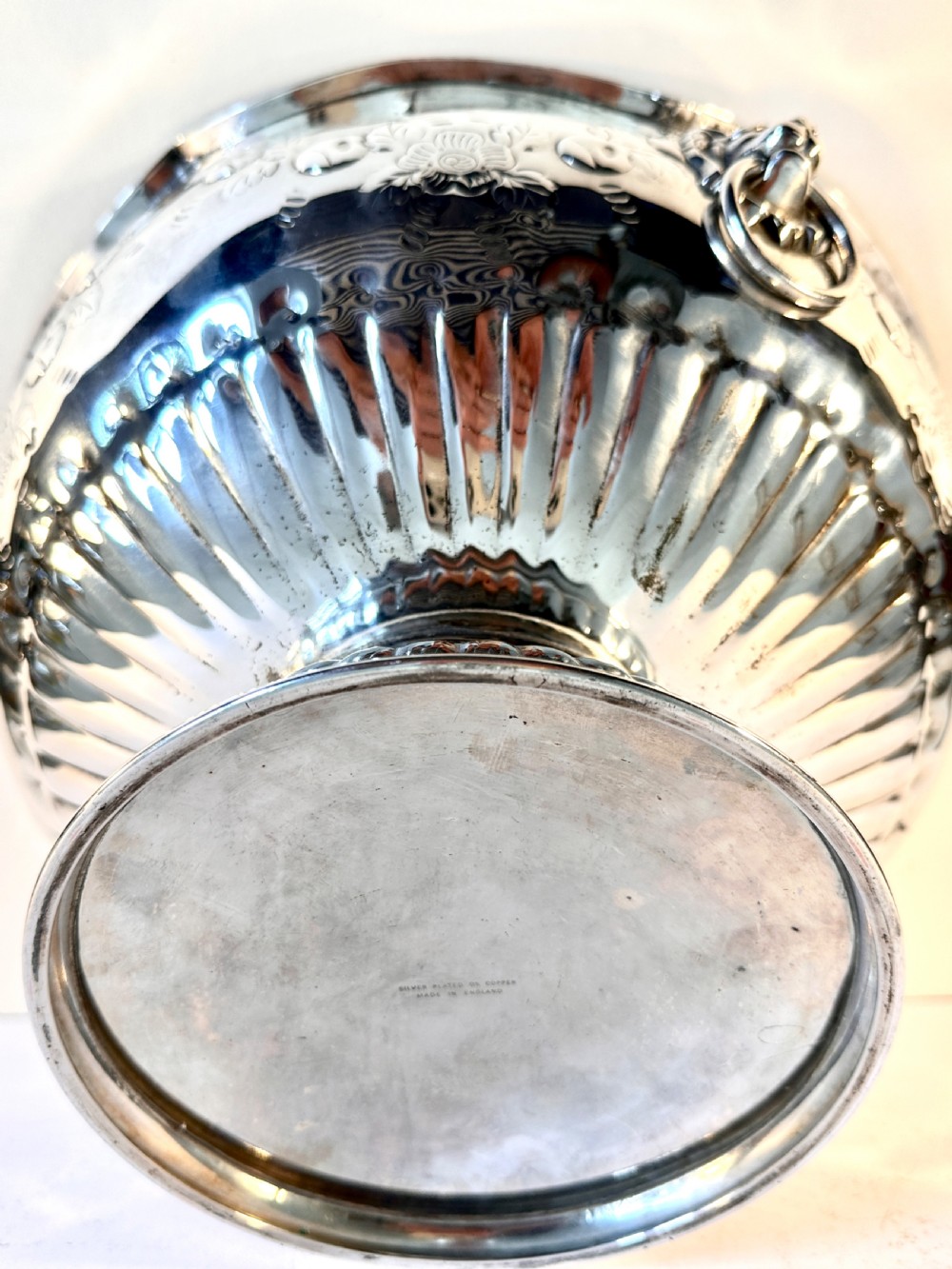 A silver-plated pedestal punch bowl featuring embossed floral repousse decoration, a scalloped rim, and twin lion mask drop-ring handles. View X