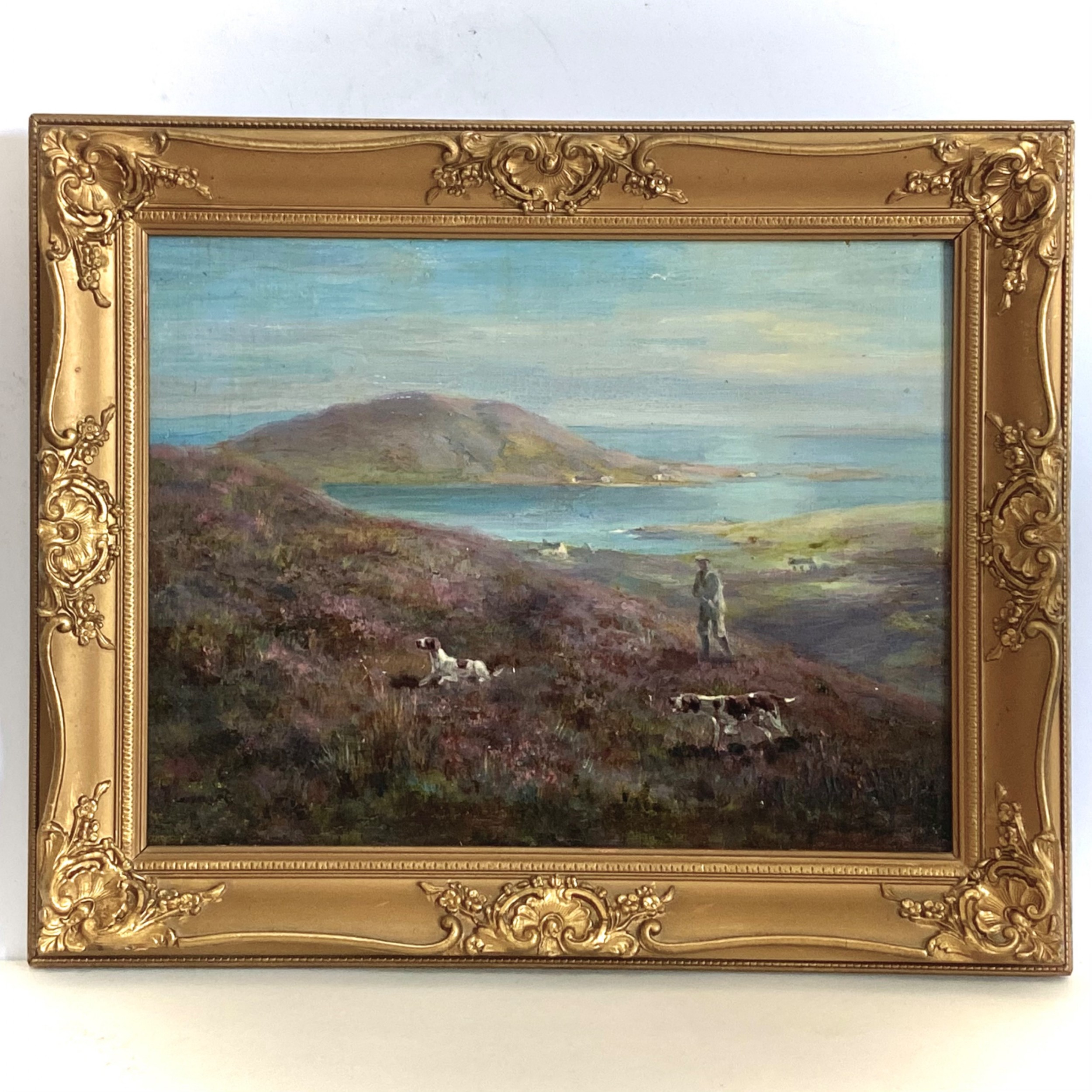 An antique oil painting on canvas depicting a hunter and gundogs in a heather moorland landscape, housed in an ornate gold gilt frame.