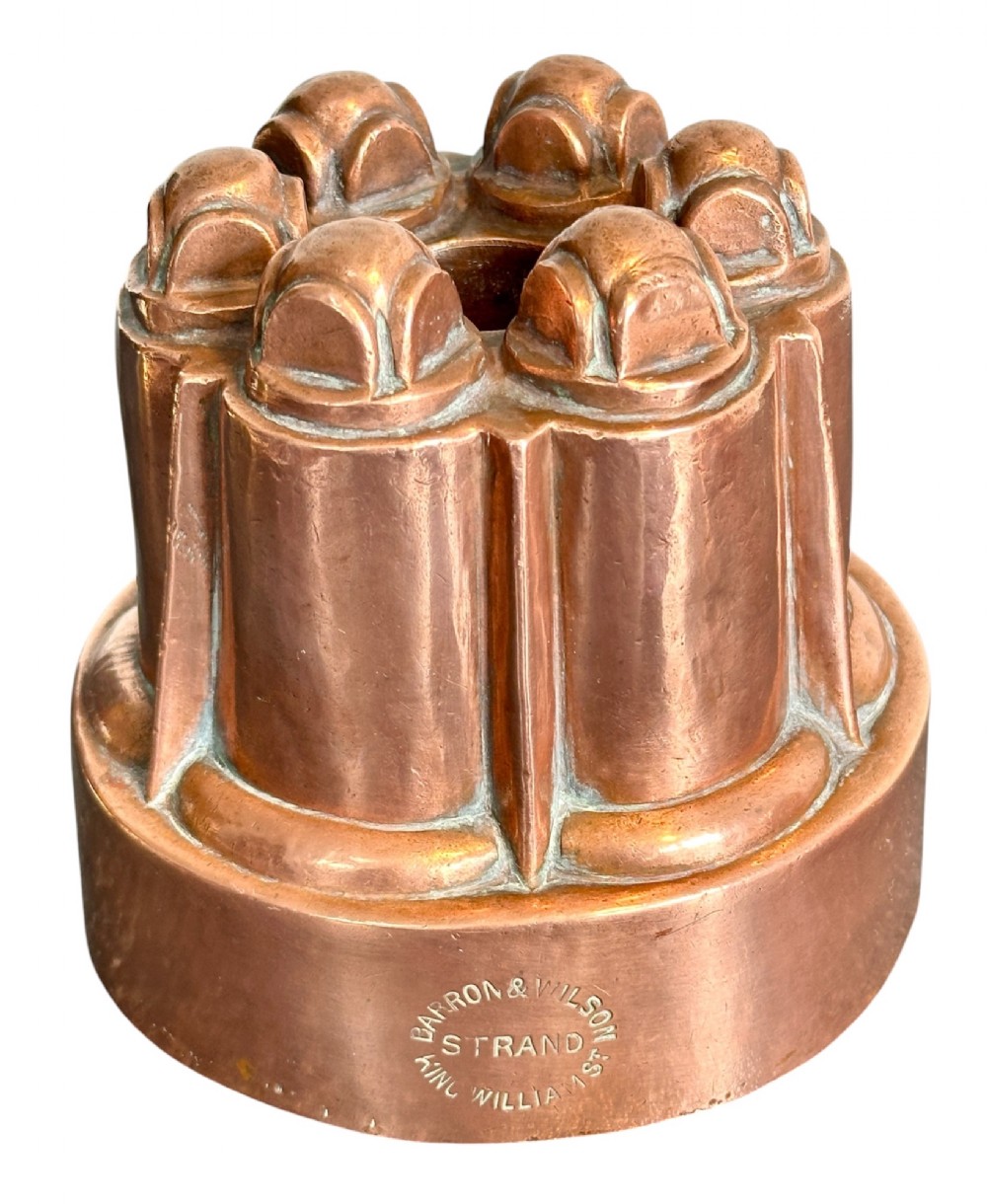 A Victorian stamped copper jelly mould featuring a multi-columned tiered architectural design with a central aperture.