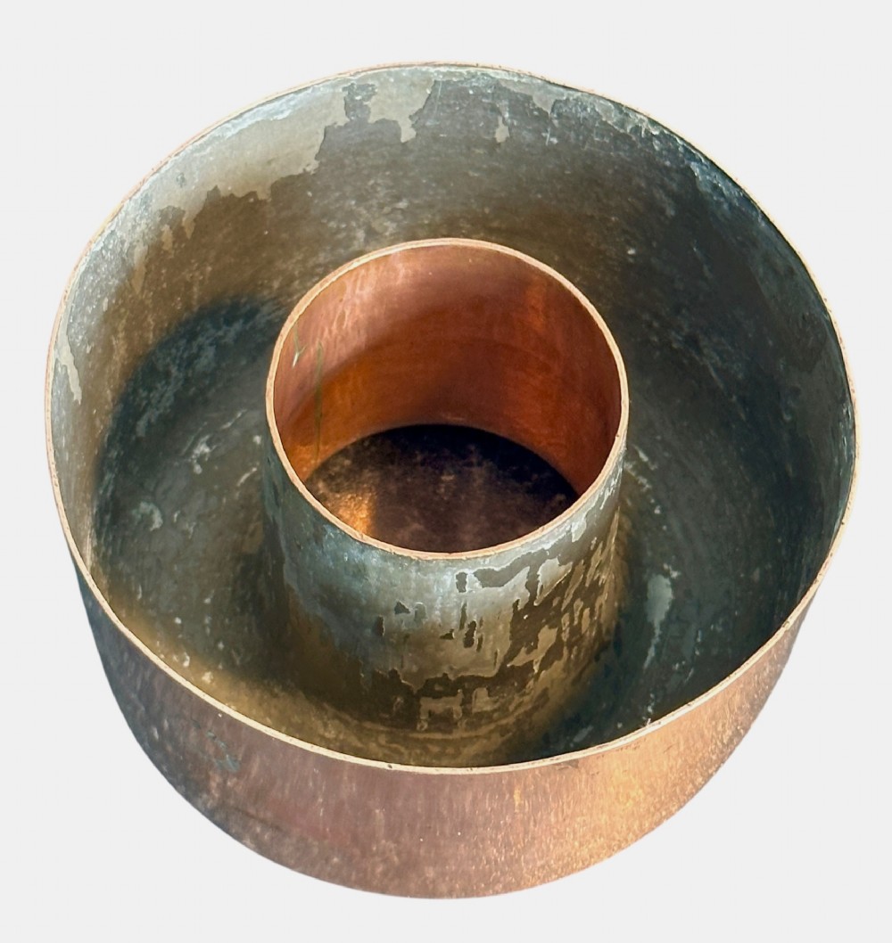 A cylindrical polished copper jelly mould with a smooth exterior and central ring well. View III