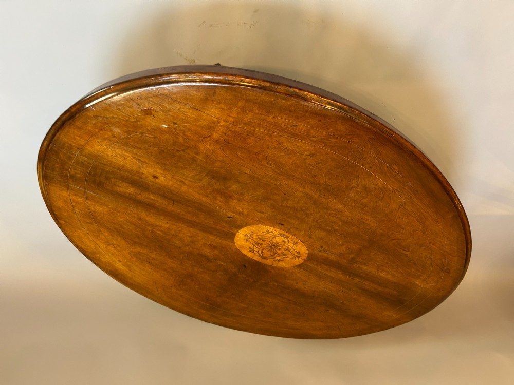 An oval Victorian walnut coffee table featuring a central floral marquetry inlay motif and carved splayed legs. View II