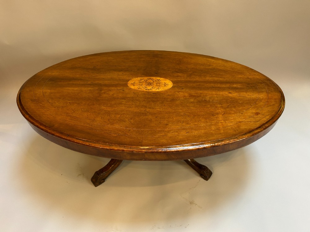 An oval Victorian walnut coffee table featuring a central floral marquetry inlay motif and carved splayed legs. View III