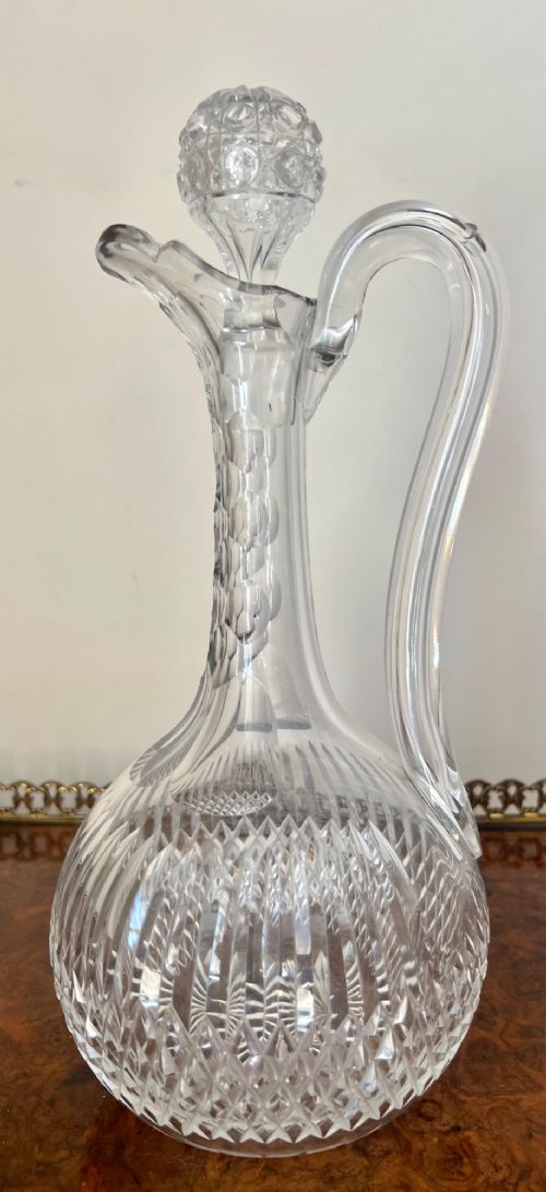 An Edwardian clear cut glass claret jug featuring a diamond-cut pattern body, an elongated handle, and a faceted spherical stopper. View IX
