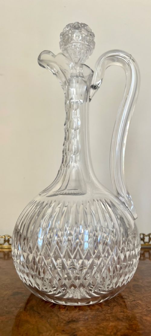 An Edwardian clear cut glass claret jug featuring a diamond-cut pattern body, an elongated handle, and a faceted spherical stopper. View X