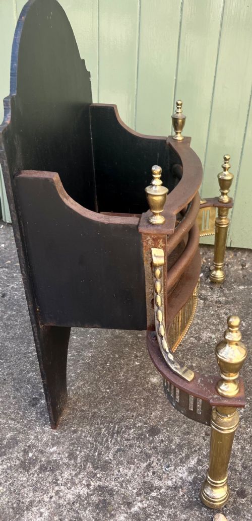 An Adam style brass and cast iron fire grate featuring a serpentine pierced front apron, urn-shaped finials, and a curved black backplate. View VII