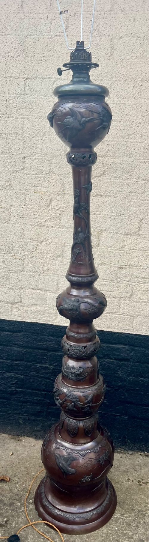A tall Japanese Meiji period dark bronze floor lamp featuring high-relief relief castings of birds and floral branches along a baluster column. View XV