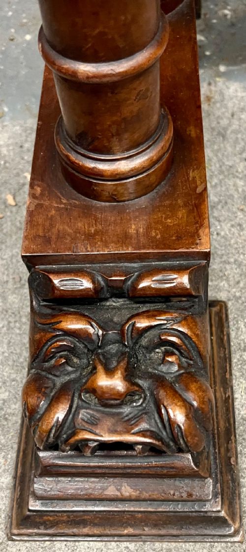 A carved Spanish vargueno cabinet in dark wood, featuring relief figures on the drop-front flap, decorative brass hardware, and a turned trestle stand. View X