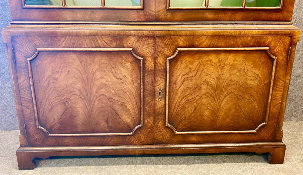 A George I style warm brown walnut bookcase featuring two upper arched glazed doors with green lining and two lower figured walnut panelled doors on bracket feet. View VI