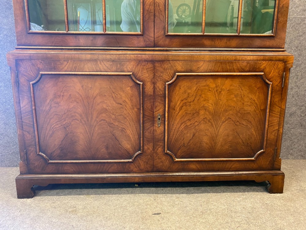 A George I style warm brown walnut bookcase featuring two upper arched glazed doors with green lining and two lower figured walnut panelled doors on bracket feet. View VII