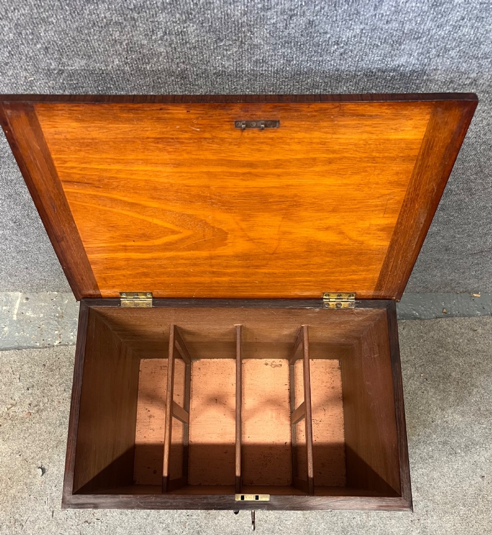 A low rectangular antique rosewood cellarette cabinet with twin panelled doors framed by beaded moulding, resting on turned feet with brass castors. View II