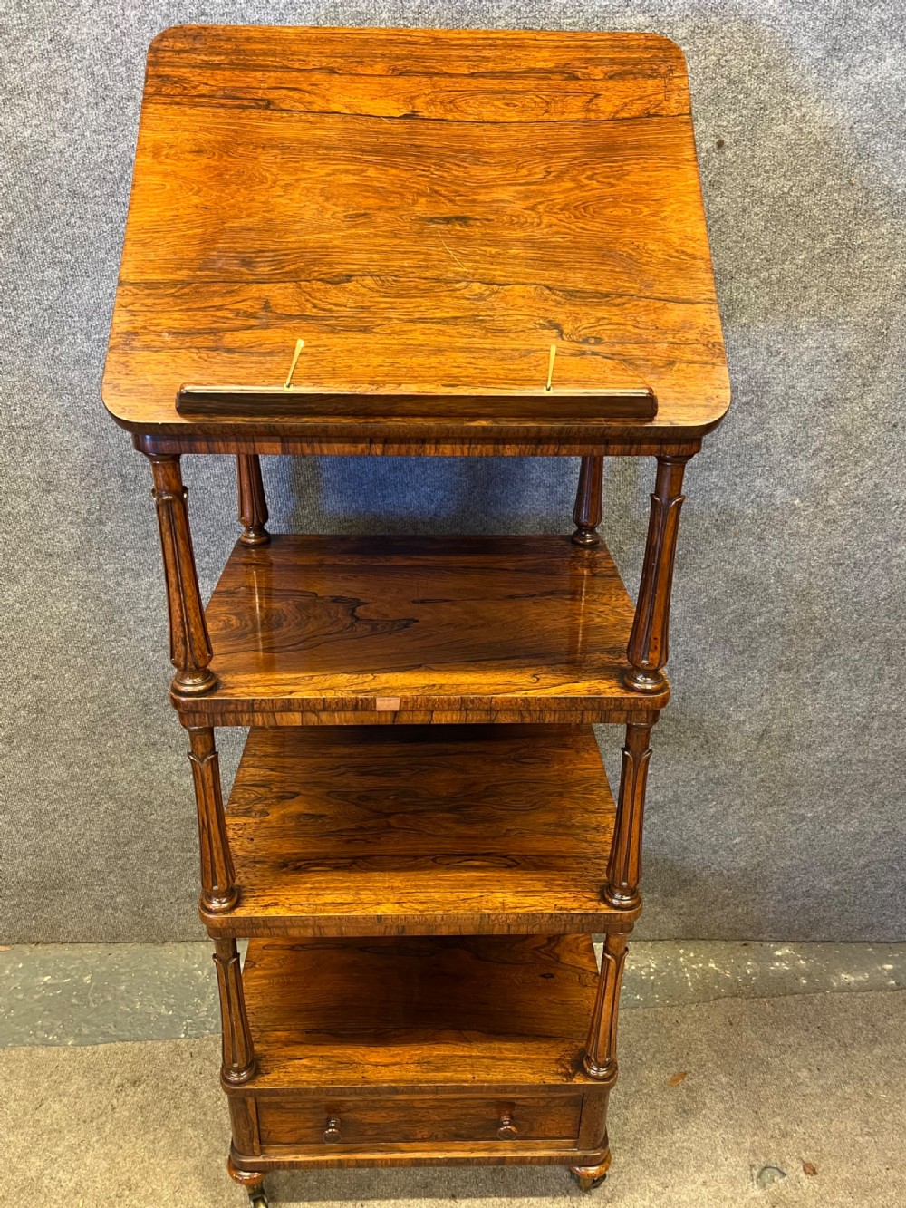 A four-tier rosewood whatnot featuring an adjustable angled top reading slope, fluted supports, a bottom drawer, and brass castors. View III