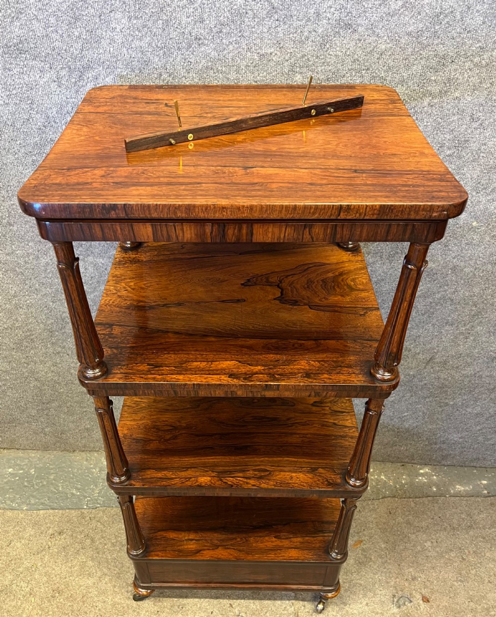 A four-tier rosewood whatnot featuring an adjustable angled top reading slope, fluted supports, a bottom drawer, and brass castors. View XI
