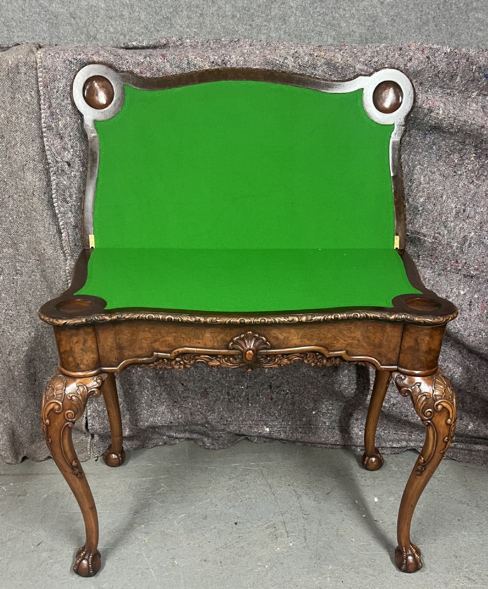 A burr walnut card table featuring a serpentine top with crossbanded borders, an ornate shell-carved apron, and cabriole legs ending in ball and claw feet. View II