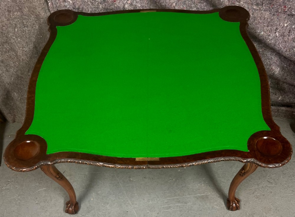A burr walnut card table featuring a serpentine top with crossbanded borders, an ornate shell-carved apron, and cabriole legs ending in ball and claw feet. View V