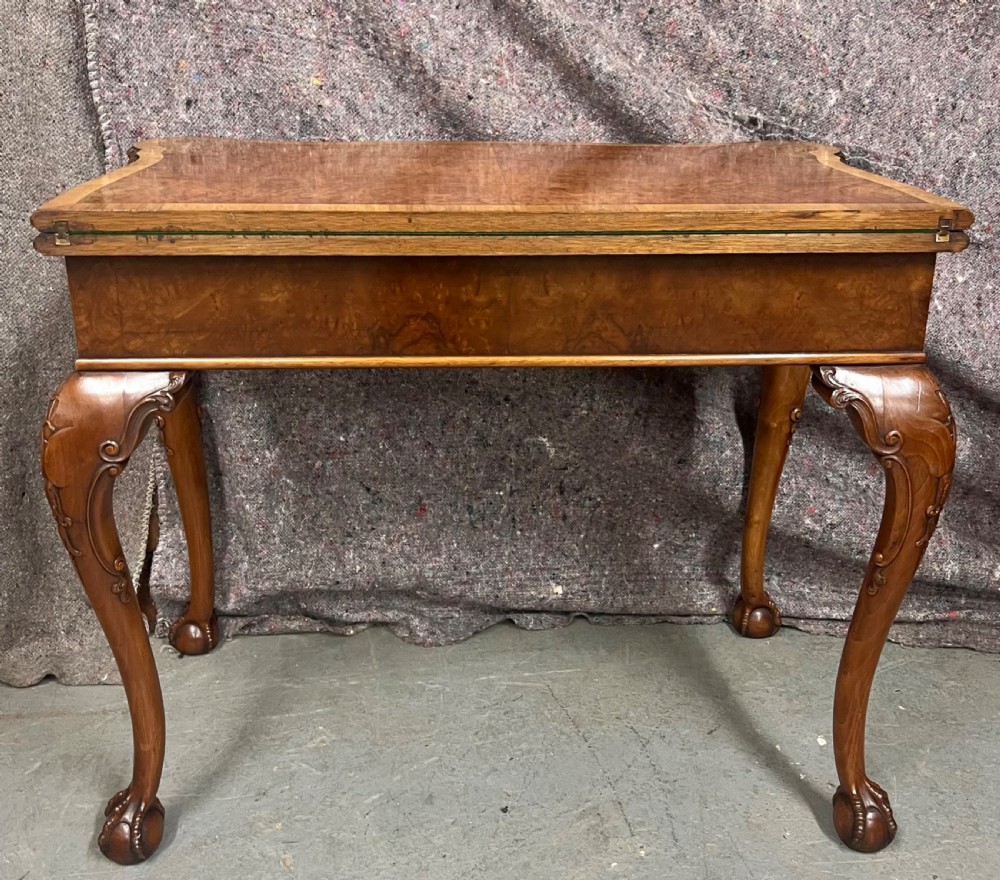 A burr walnut card table featuring a serpentine top with crossbanded borders, an ornate shell-carved apron, and cabriole legs ending in ball and claw feet. View XIII