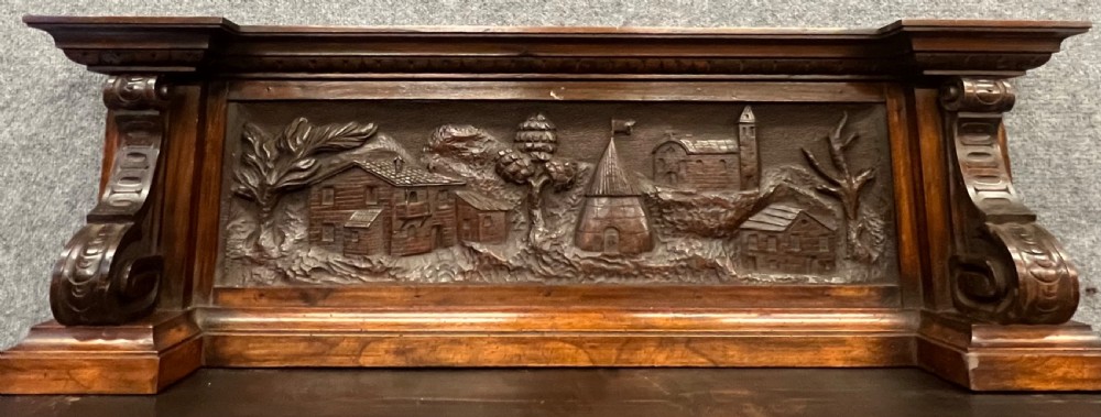 A heavily carved dark walnut cabinet featuring figurative reliefs, caryatid supports, mask motifs, and an architectural cresting. View VIII