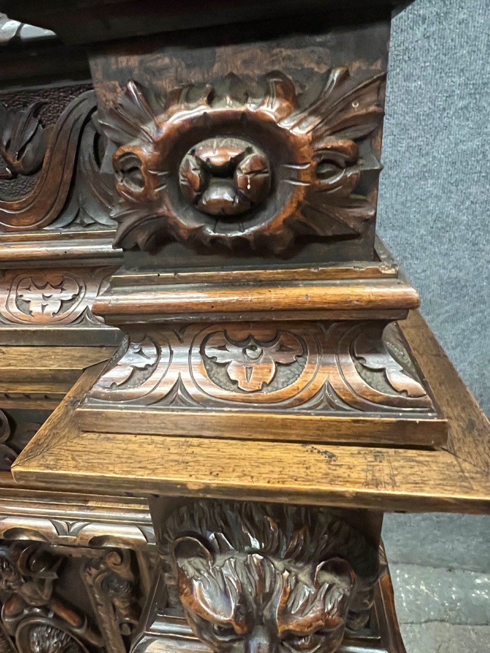 A heavily carved dark walnut cabinet featuring figurative reliefs, caryatid supports, mask motifs, and an architectural cresting. View XVI