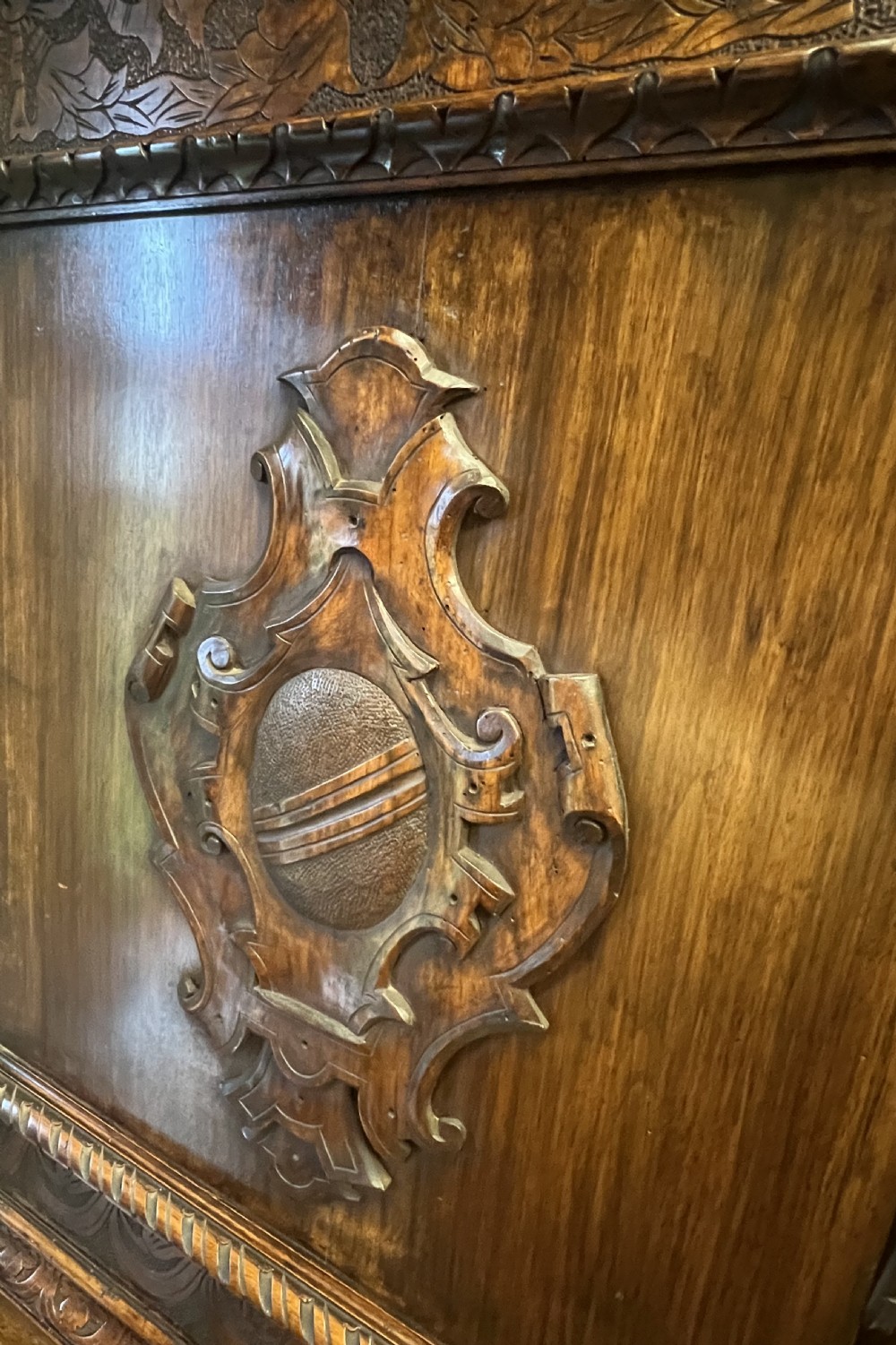 A heavily carved dark walnut cabinet featuring figurative reliefs, caryatid supports, mask motifs, and an architectural cresting. View XIX