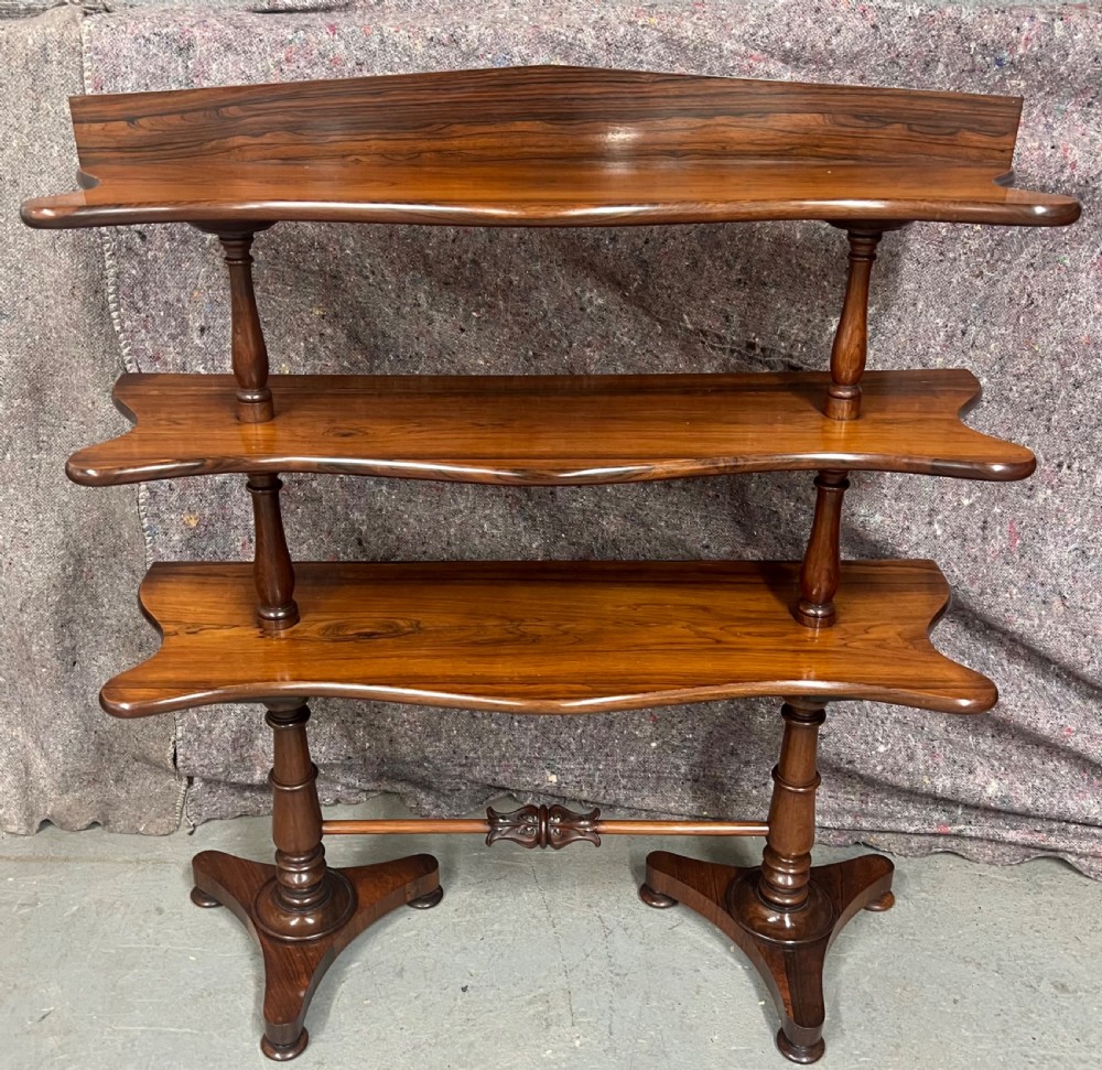 A 19th-century rosewood three-tier whatnot with serpentine shaped shelves and turned column supports.