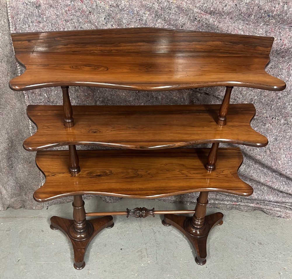 A 19th-century rosewood three-tier whatnot with serpentine shaped shelves and turned column supports. View II