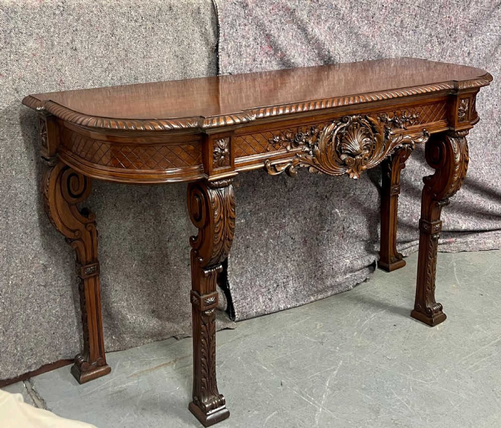 An antique dark brown carved wood console table featuring a shell motif central frieze and detailed scrolled legs. View II