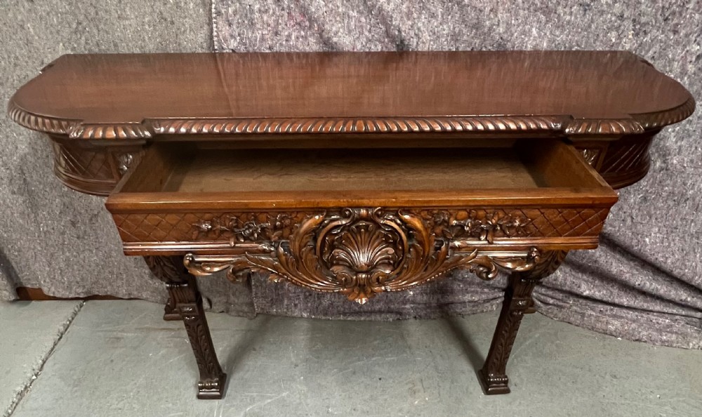An antique dark brown carved wood console table featuring a shell motif central frieze and detailed scrolled legs. View III