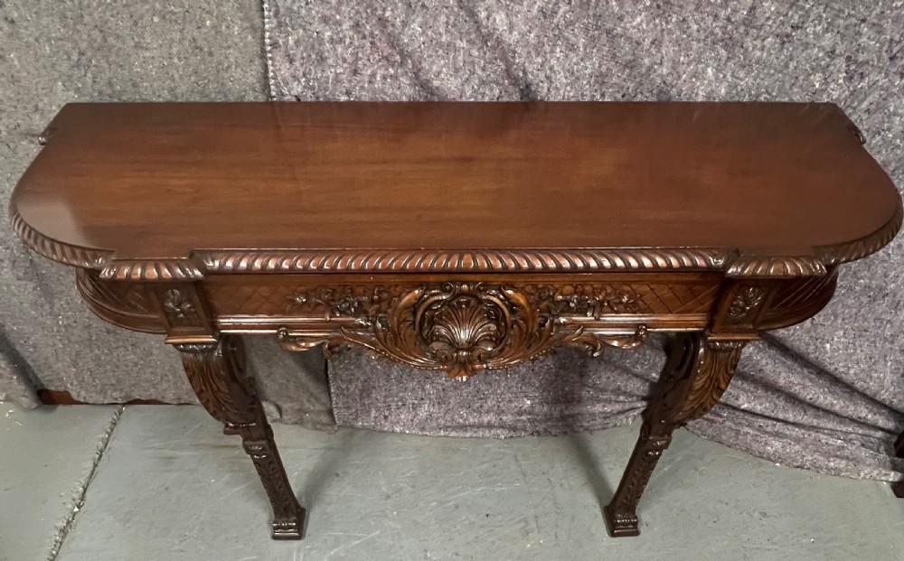 An antique dark brown carved wood console table featuring a shell motif central frieze and detailed scrolled legs. View IV